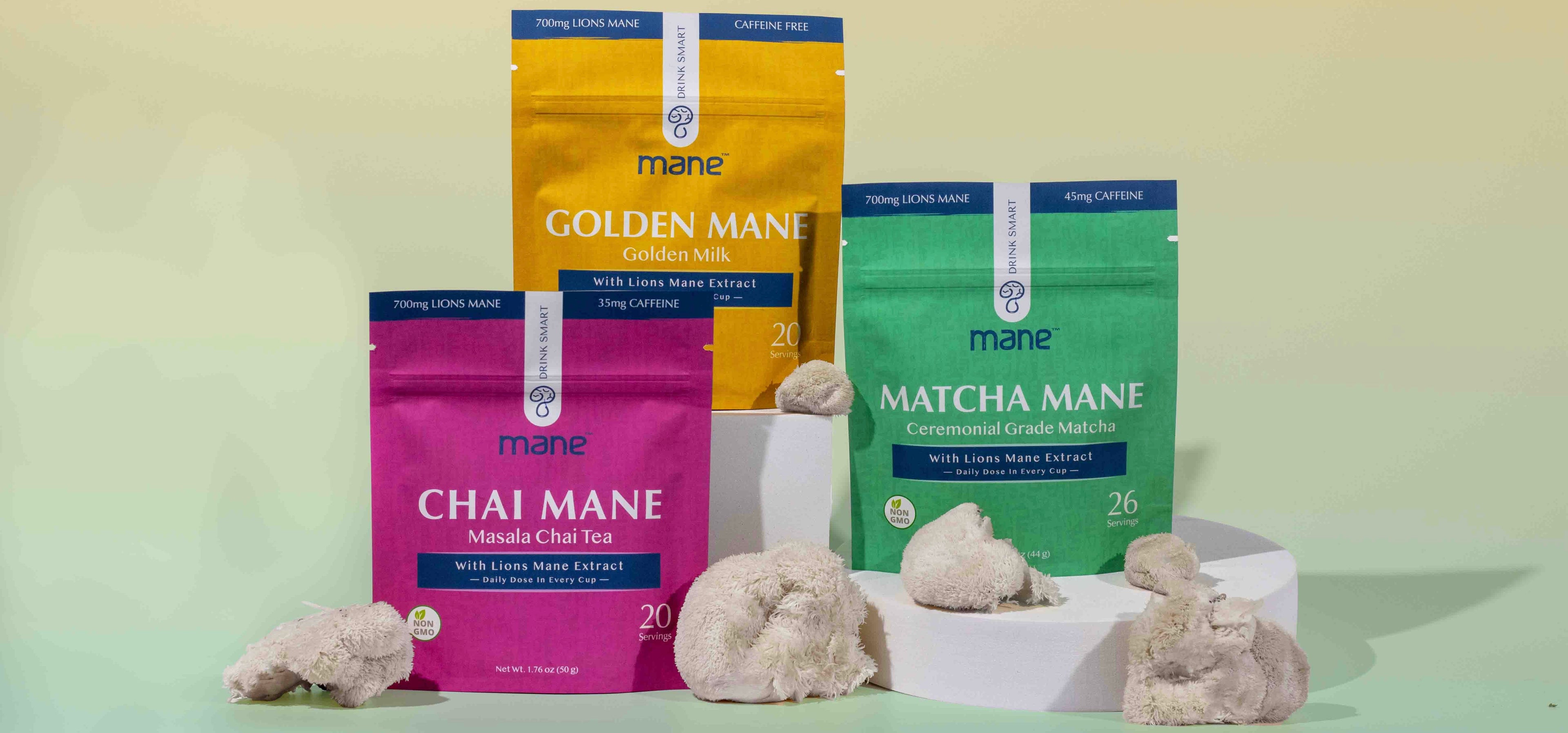 three packages of chai, golden milk and matcha, stacked with lions mane and yellow and green gradient background