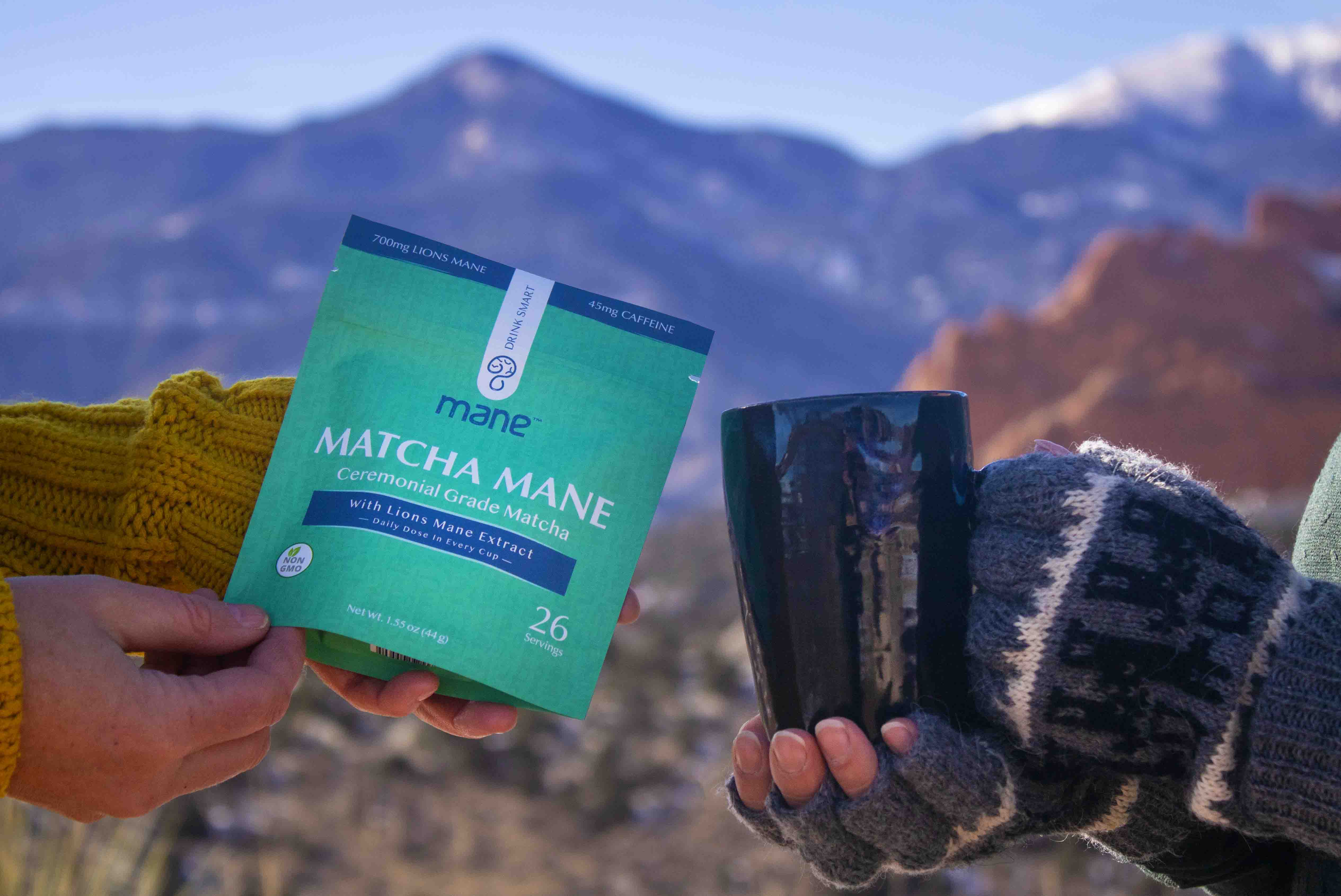 Person holding a package of Matcha Mane supplement with a scenic mountain background